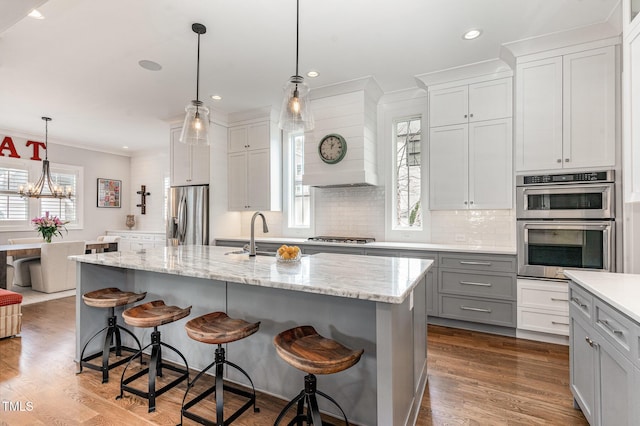 kitchen featuring a kitchen island with sink, sink, pendant lighting, and stainless steel appliances