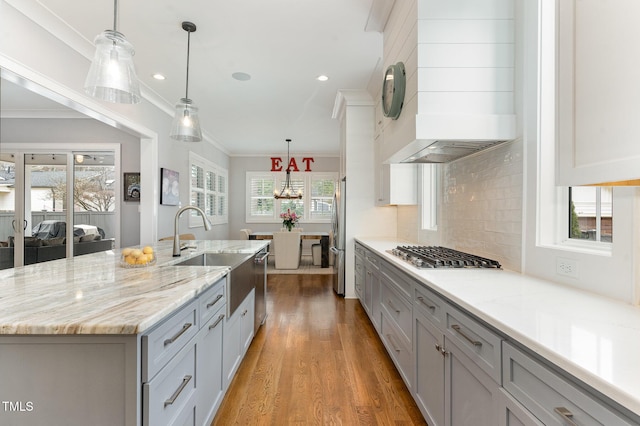 kitchen featuring gray cabinetry, appliances with stainless steel finishes, decorative light fixtures, and a large island with sink