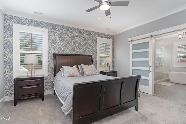 bedroom with ceiling fan, light colored carpet, ensuite bathroom, and a barn door