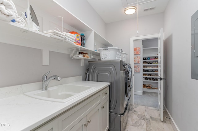 clothes washing area featuring cabinets, sink, and independent washer and dryer