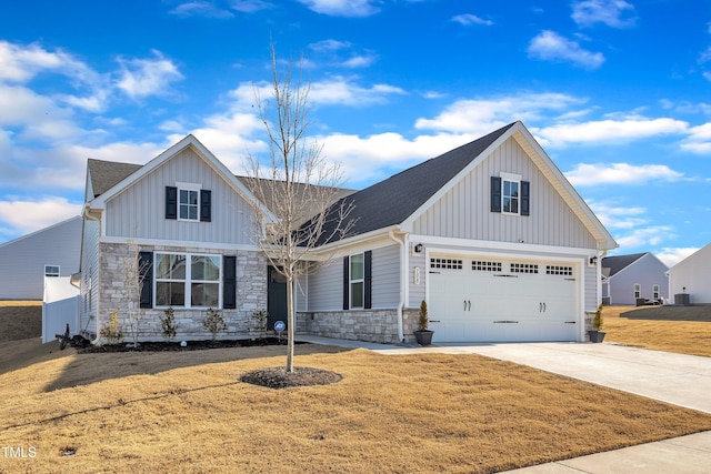 view of front of house with board and batten siding, a front yard, concrete driveway, and stone siding