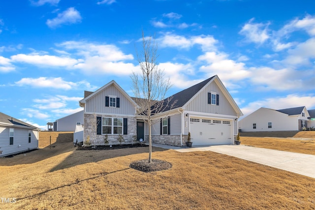 view of front of home with board and batten siding, stone siding, a front lawn, and concrete driveway