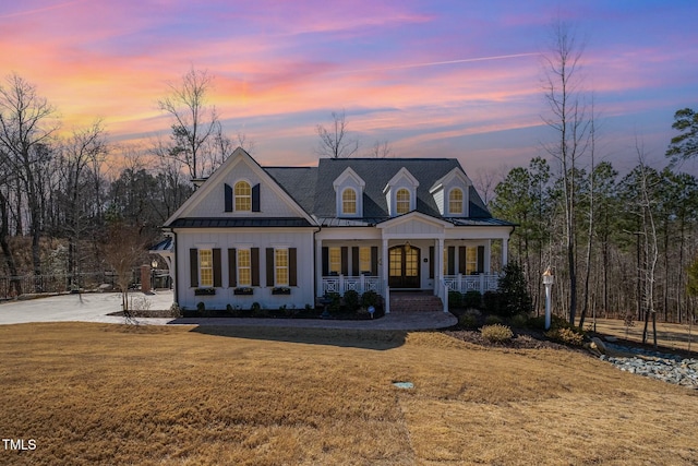 view of front of house with a standing seam roof, metal roof, a porch, and a front yard