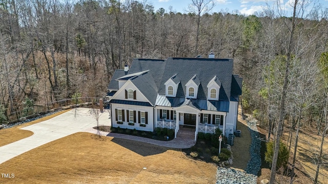 new england style home featuring central AC unit, a front yard, and covered porch