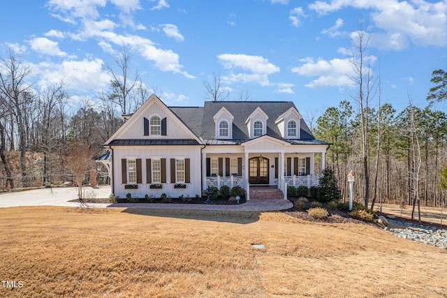 view of front of house with a porch, a front yard, a standing seam roof, and metal roof