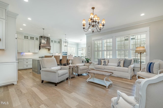 living area featuring crown molding, recessed lighting, light wood-style flooring, and a notable chandelier