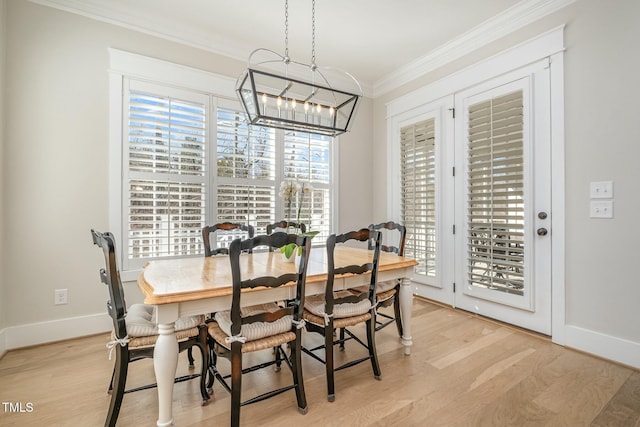 dining room featuring a chandelier, baseboards, crown molding, and light wood finished floors