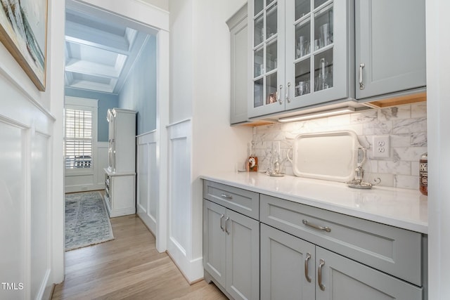 bar featuring gray cabinets, tasteful backsplash, beamed ceiling, crown molding, and light wood-type flooring