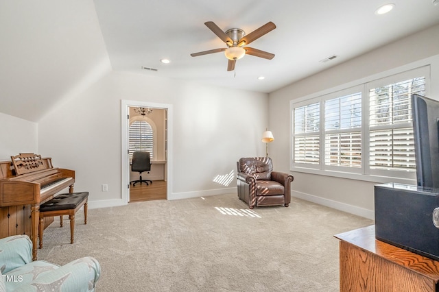 sitting room with ceiling fan, vaulted ceiling, light colored carpet, and a healthy amount of sunlight