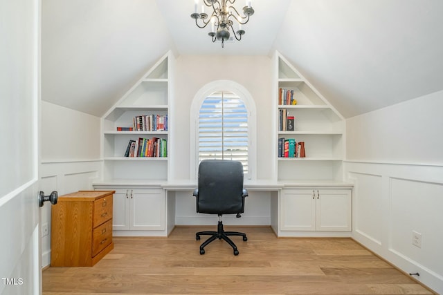 office area featuring built in shelves, lofted ceiling, built in desk, and light wood finished floors