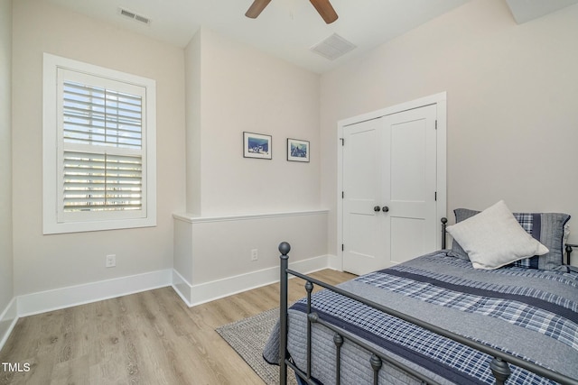 bedroom with a ceiling fan, baseboards, visible vents, and wood finished floors