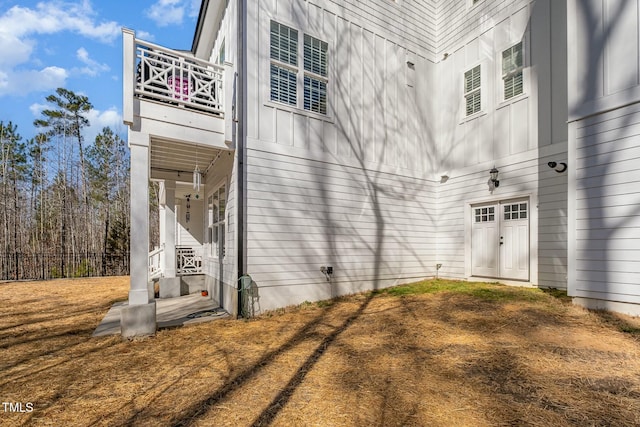 view of side of property featuring board and batten siding and a balcony