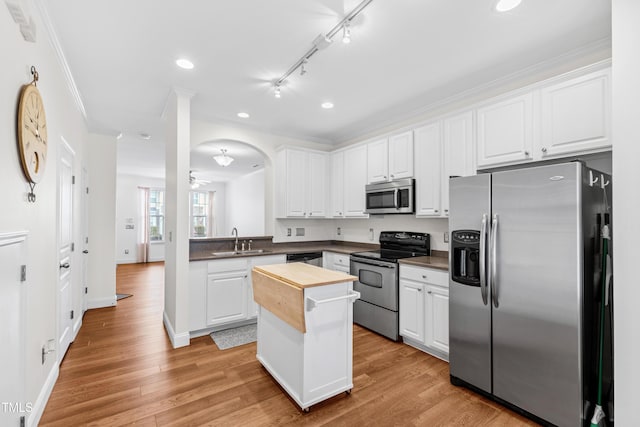 kitchen with stainless steel appliances, a kitchen island, sink, and white cabinets