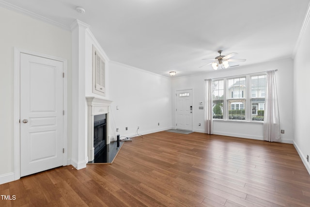 unfurnished living room featuring wood-type flooring, ornamental molding, and ceiling fan