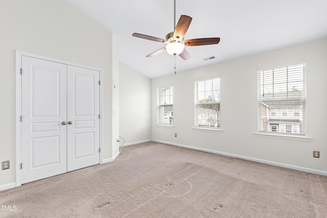 empty room featuring ceiling fan, lofted ceiling, and light carpet