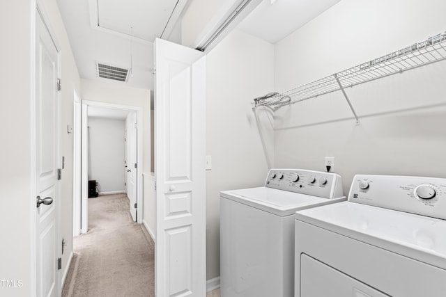 clothes washing area featuring light colored carpet and washer and dryer