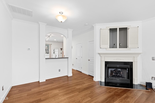 unfurnished living room with crown molding and wood-type flooring