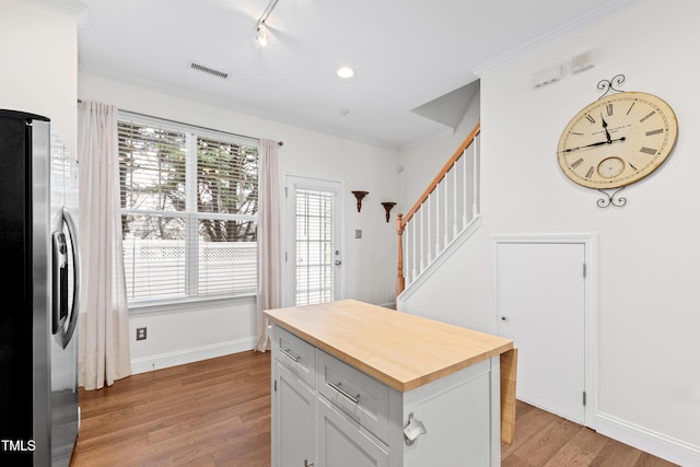 kitchen featuring crown molding, light hardwood / wood-style flooring, white cabinetry, track lighting, and stainless steel fridge with ice dispenser