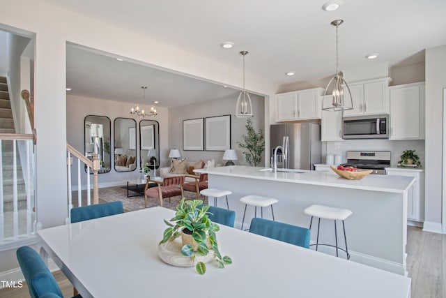 dining area with sink, a notable chandelier, and light hardwood / wood-style floors