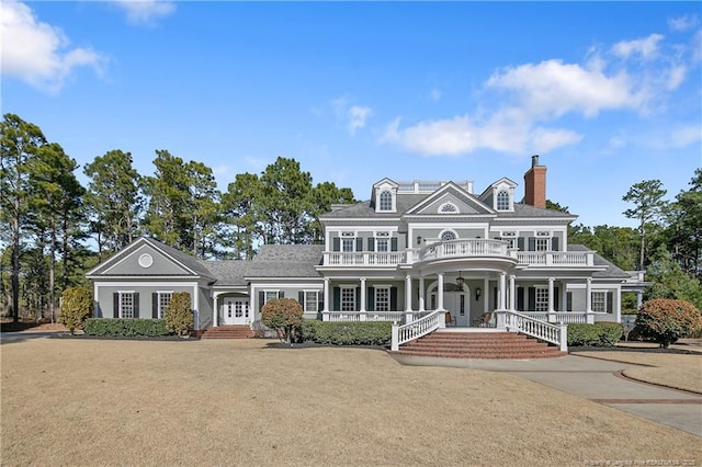 view of front of house with a balcony, a front lawn, and french doors