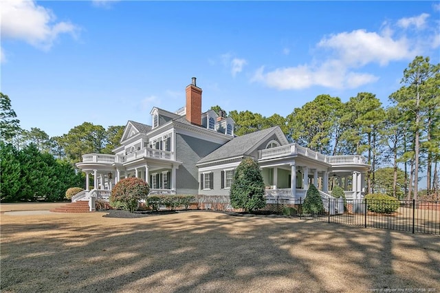 rear view of house featuring a balcony and a porch