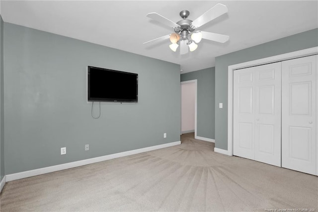 unfurnished bedroom featuring light colored carpet, ceiling fan, and a closet