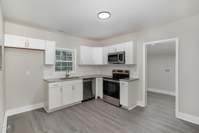 kitchen with backsplash, appliances with stainless steel finishes, white cabinetry, and a sink