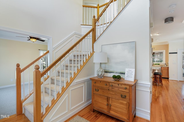 stairway with hardwood / wood-style flooring, crown molding, and ceiling fan