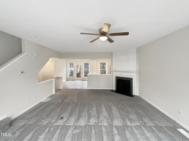 unfurnished living room with ceiling fan, carpet flooring, and a large fireplace