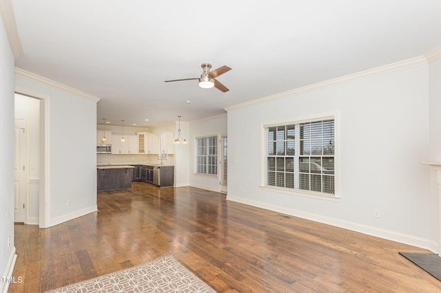 unfurnished living room with dark wood-type flooring, ceiling fan, crown molding, and sink