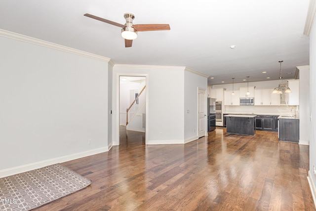 unfurnished living room featuring ornamental molding, dark hardwood / wood-style floors, sink, and ceiling fan