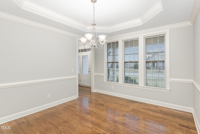 unfurnished dining area featuring hardwood / wood-style flooring, a raised ceiling, and a chandelier