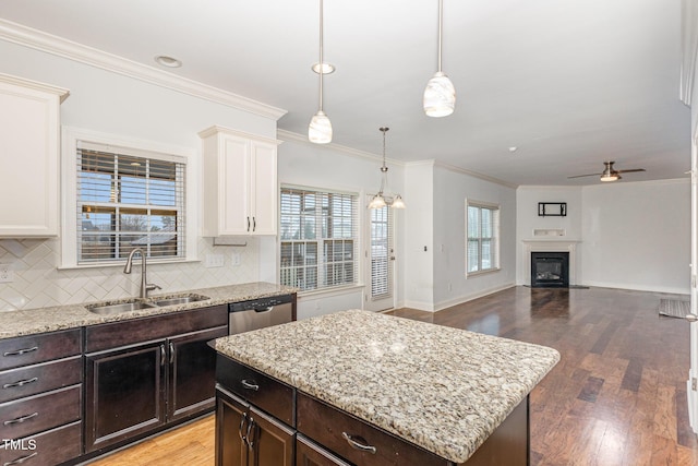 kitchen featuring decorative light fixtures, white cabinetry, sink, a center island, and stainless steel dishwasher