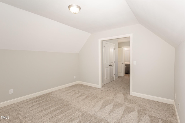 additional living space featuring light colored carpet and lofted ceiling