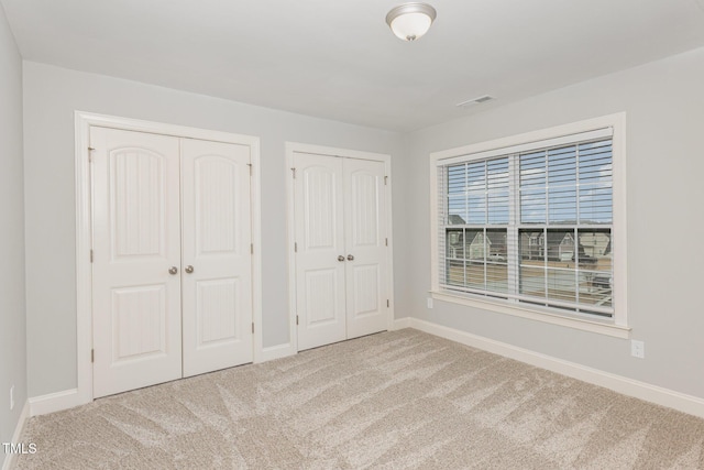 unfurnished bedroom with multiple closets and carpet flooring