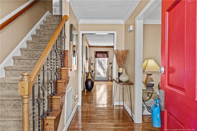 foyer entrance with ornamental molding, hardwood / wood-style floors, and a textured ceiling