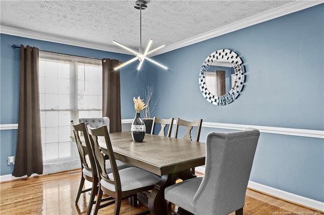 dining space with crown molding, an inviting chandelier, light hardwood / wood-style flooring, and a textured ceiling