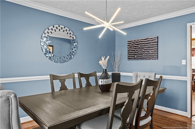 dining room with ornamental molding, wood-type flooring, a notable chandelier, and a textured ceiling