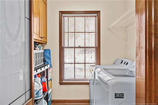 clothes washing area featuring independent washer and dryer and cabinets