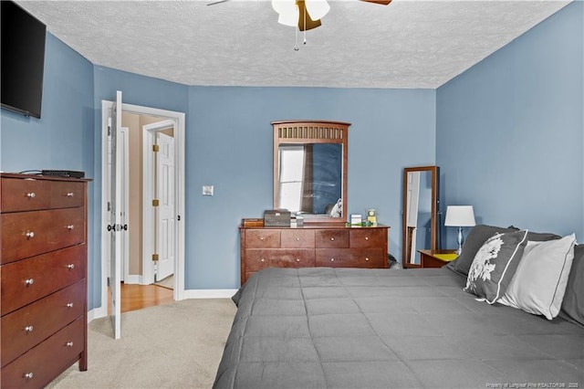 carpeted bedroom with ceiling fan and a textured ceiling