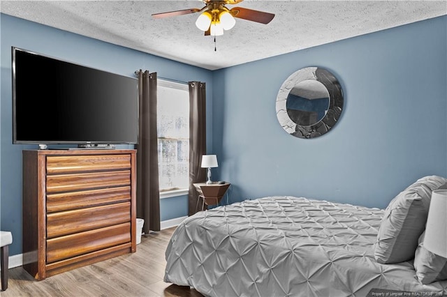 bedroom featuring ceiling fan, a textured ceiling, and light wood-type flooring