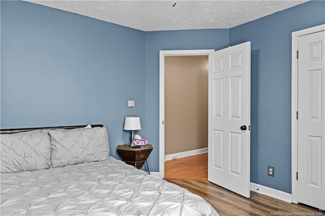 bedroom with a textured ceiling and light hardwood / wood-style floors