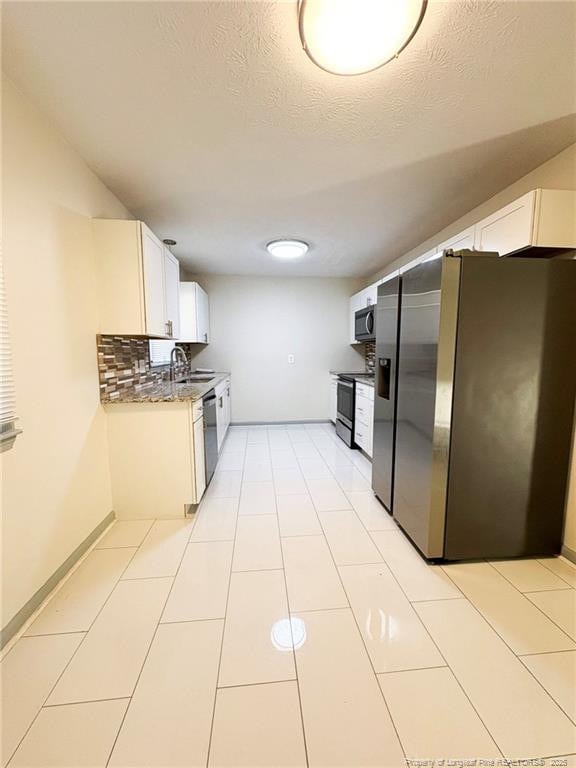 kitchen featuring sink, appliances with stainless steel finishes, white cabinetry, a textured ceiling, and decorative backsplash