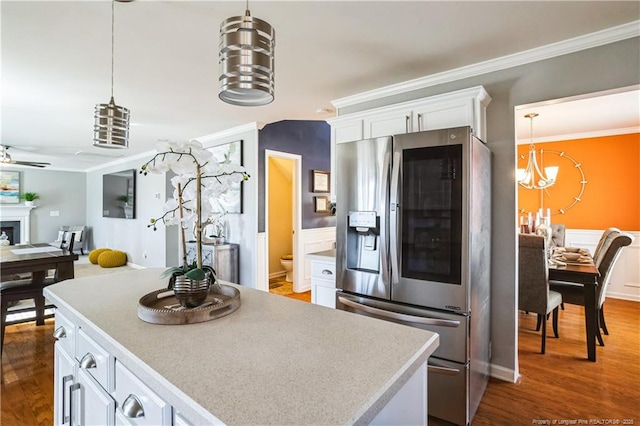 kitchen featuring pendant lighting, stainless steel refrigerator, white cabinets, dark hardwood / wood-style flooring, and ornamental molding