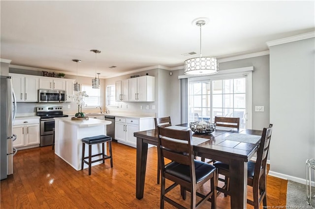 dining area featuring hardwood / wood-style flooring, ornamental molding, and sink