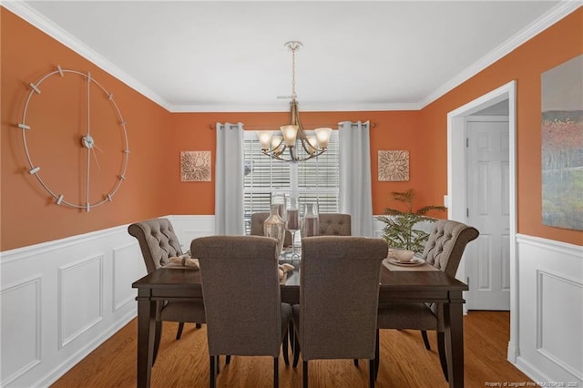 dining area with crown molding, hardwood / wood-style floors, and an inviting chandelier