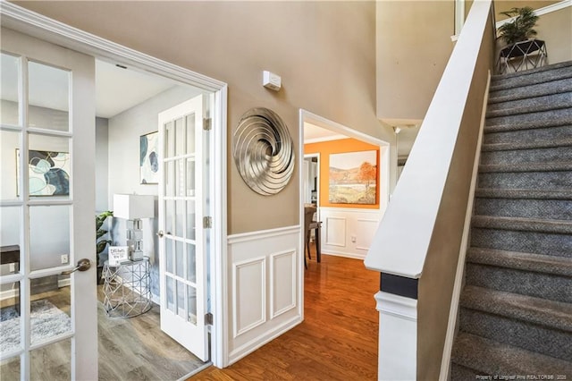 stairs with hardwood / wood-style floors and french doors