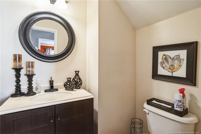 bathroom with vanity, toilet, and vaulted ceiling