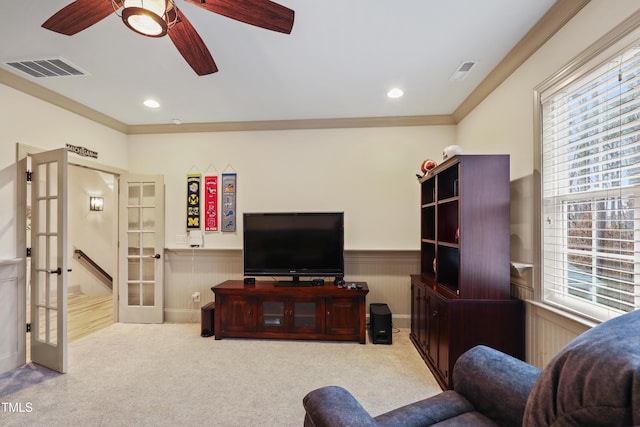 carpeted living room with ornamental molding, ceiling fan, and french doors