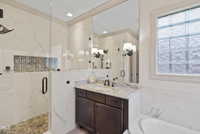 bathroom with vanity, plenty of natural light, shower with separate bathtub, and tile walls